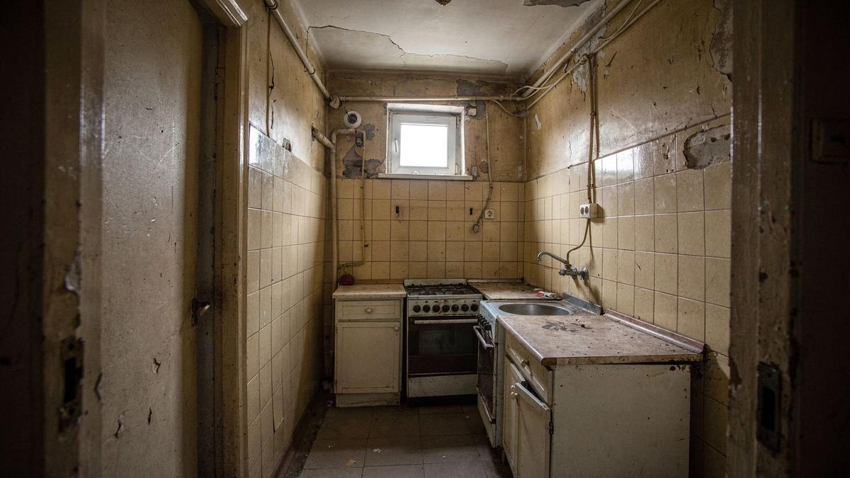 Kitchen and corridor before renovation with a closed layout, dated tiles and old wiring
